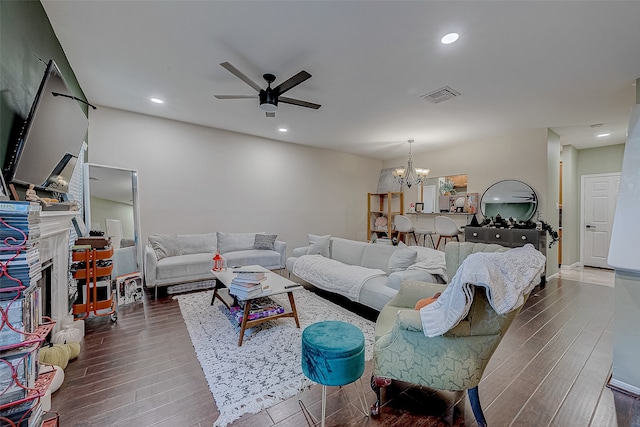 living room with ceiling fan with notable chandelier and dark hardwood / wood-style floors