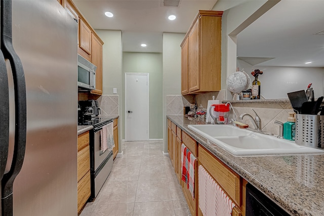 kitchen with appliances with stainless steel finishes, backsplash, light tile patterned floors, and sink