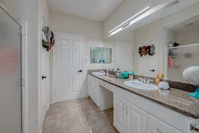 bathroom with a shower with door, vanity, and tile patterned flooring