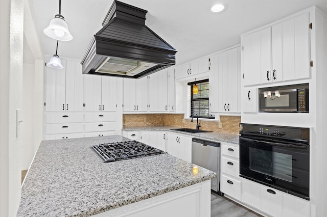 kitchen featuring custom exhaust hood, black appliances, sink, hanging light fixtures, and white cabinetry