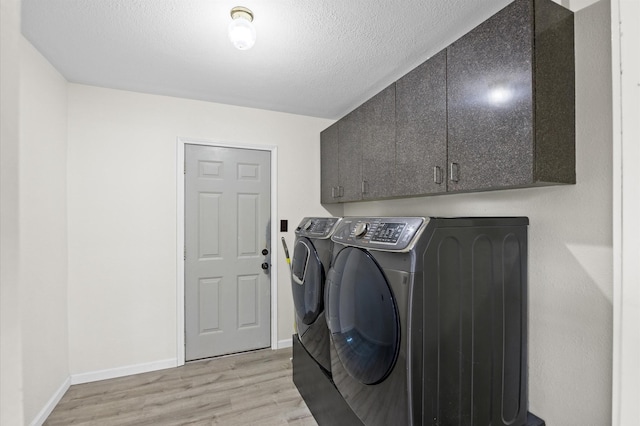 laundry room with light hardwood / wood-style flooring, cabinets, a textured ceiling, and independent washer and dryer