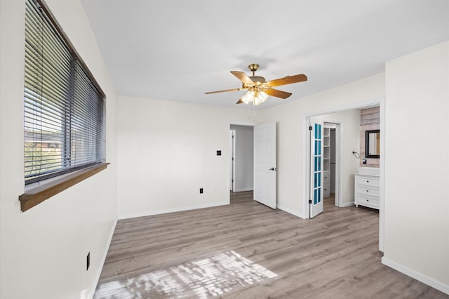 unfurnished bedroom featuring ceiling fan, ensuite bathroom, and light hardwood / wood-style flooring