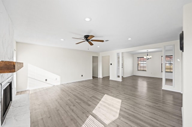 unfurnished living room featuring wood-type flooring and ceiling fan with notable chandelier