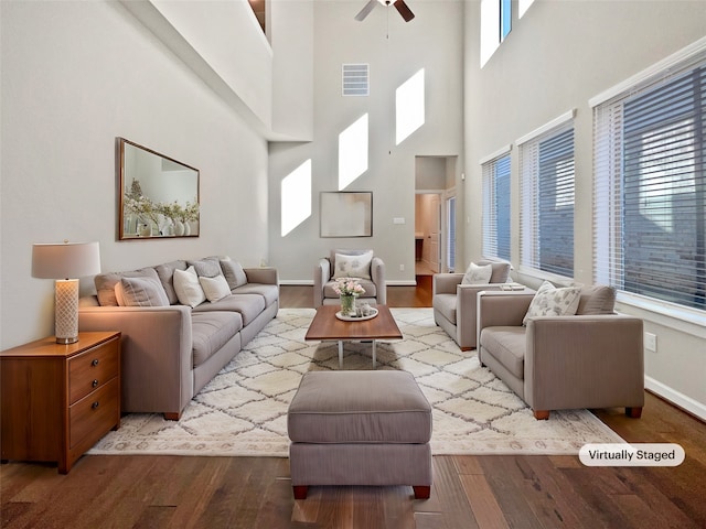 living room featuring ceiling fan, a towering ceiling, and light wood-type flooring