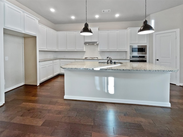 kitchen featuring white cabinets, decorative light fixtures, a center island with sink, and stainless steel appliances