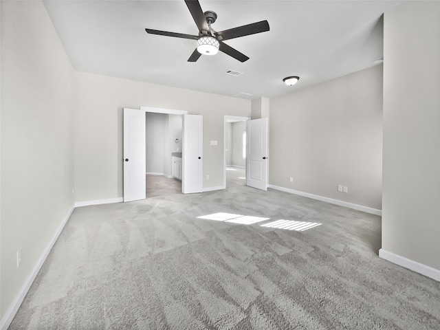 unfurnished bedroom featuring ceiling fan, light colored carpet, and connected bathroom