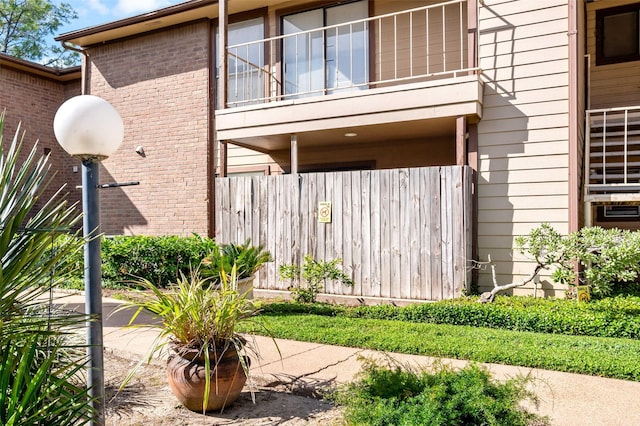 view of side of property with a balcony, fence, and brick siding