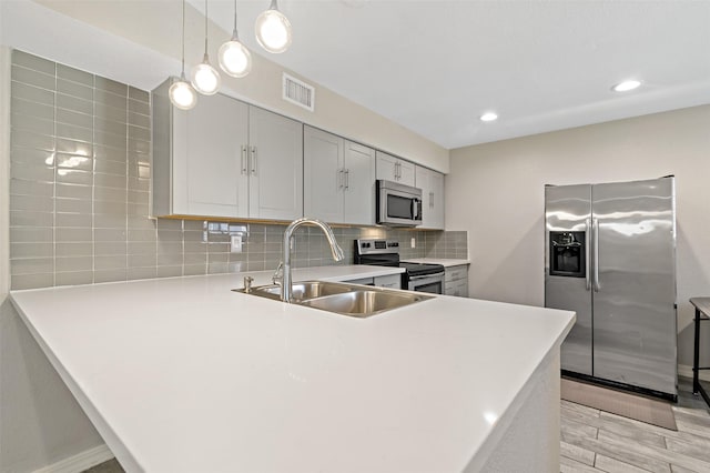 kitchen featuring light countertops, visible vents, stainless steel appliances, tasteful backsplash, and a sink