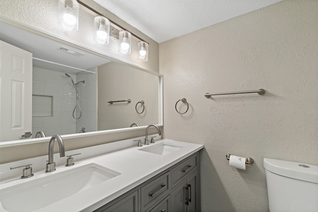 bathroom with a shower, vanity, a textured ceiling, and toilet