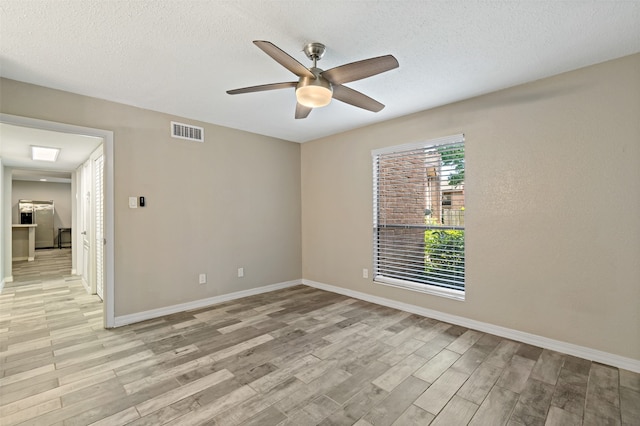 spare room with ceiling fan, light hardwood / wood-style flooring, and a textured ceiling