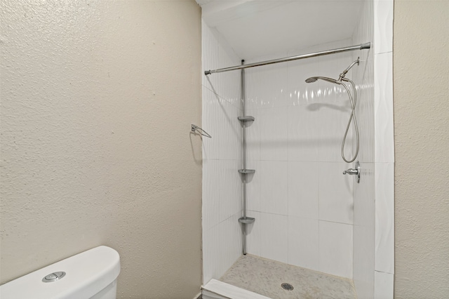 bathroom featuring toilet and a tile shower