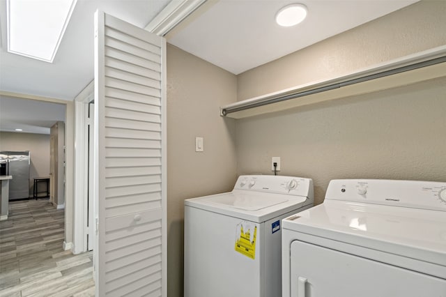 washroom with independent washer and dryer and light hardwood / wood-style flooring