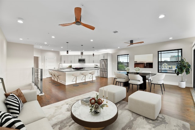 living room featuring hardwood / wood-style floors, ceiling fan, and sink