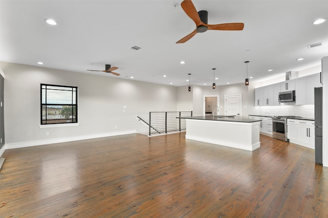 kitchen with stainless steel appliances, a kitchen island with sink, dark wood-type flooring, decorative light fixtures, and white cabinetry