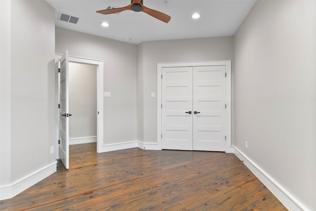 unfurnished bedroom with dark hardwood / wood-style flooring, a closet, and ceiling fan