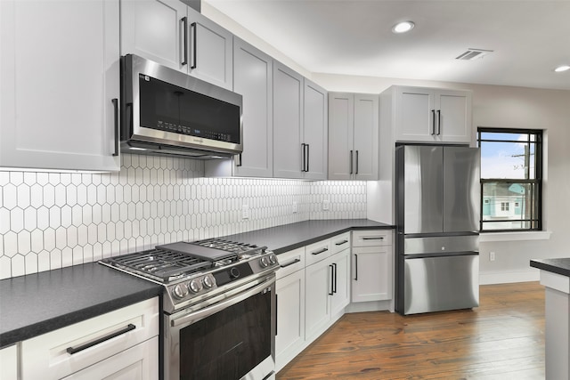 kitchen featuring decorative backsplash, gray cabinets, dark hardwood / wood-style flooring, and stainless steel appliances