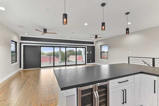 kitchen with white cabinets, decorative light fixtures, light hardwood / wood-style floors, and beverage cooler