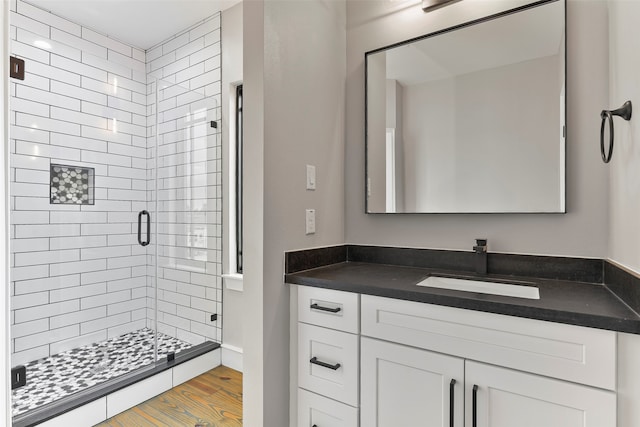 bathroom with hardwood / wood-style floors, vanity, and a shower with door