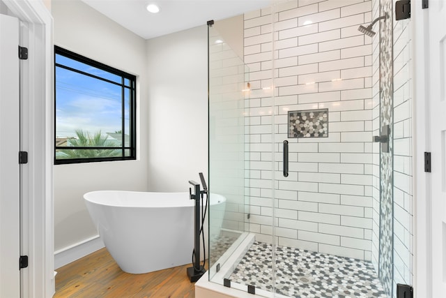 bathroom with wood-type flooring and shower with separate bathtub