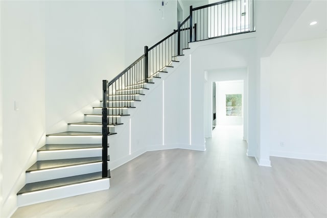 staircase with hardwood / wood-style floors and a towering ceiling