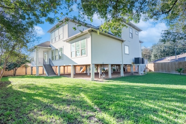 back of property with a yard and central AC