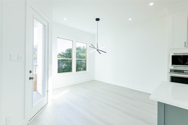 unfurnished dining area featuring a chandelier and light hardwood / wood-style floors