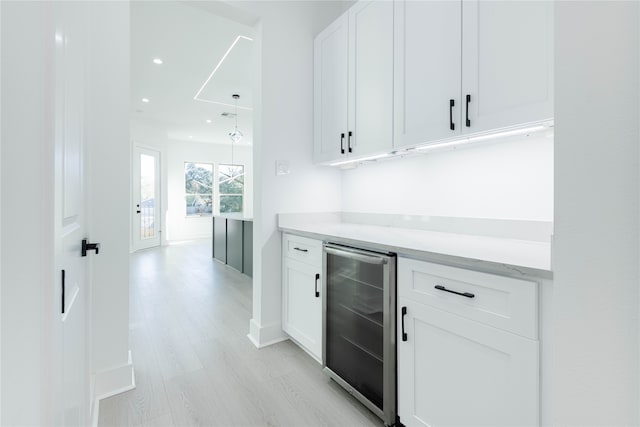 bar featuring white cabinets, light hardwood / wood-style floors, light stone countertops, and wine cooler