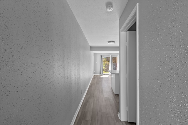 hallway featuring a textured ceiling and light hardwood / wood-style flooring