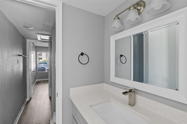 12900 Walden Rd Unit 419D, Montgomery, TX 77356 - bathroom featuring vanity, toilet, baseboards, wood finished floors, and a textured ceiling