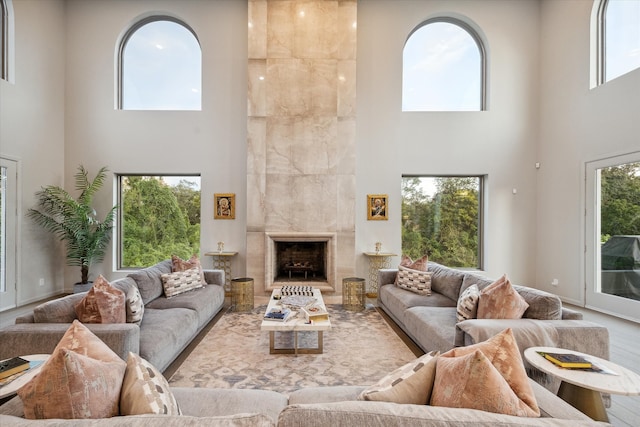 living room featuring plenty of natural light, a towering ceiling, and a fireplace