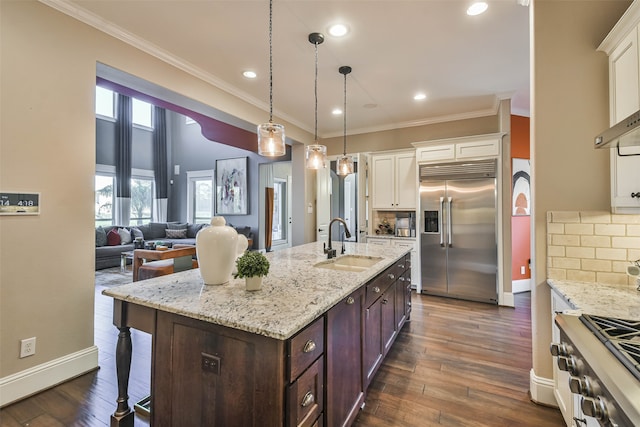 kitchen featuring sink, dark wood-type flooring, premium appliances, pendant lighting, and dark brown cabinets