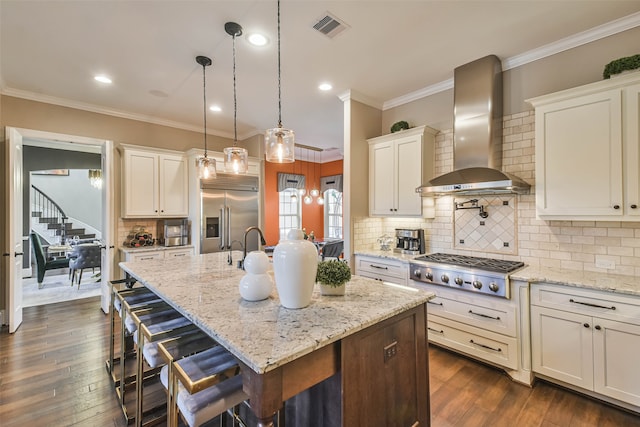 kitchen featuring wall chimney exhaust hood, dark hardwood / wood-style floors, stainless steel appliances, and a kitchen island with sink