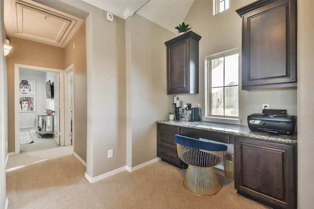 office space featuring lofted ceiling, built in desk, and light carpet