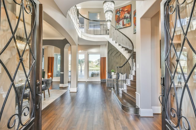 entryway with crown molding, a high ceiling, dark hardwood / wood-style floors, and an inviting chandelier