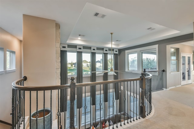 corridor with a tray ceiling and carpet