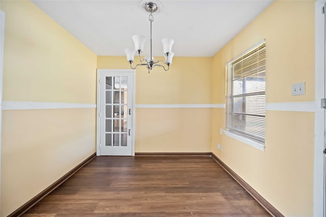 unfurnished dining area with dark wood-type flooring and a notable chandelier