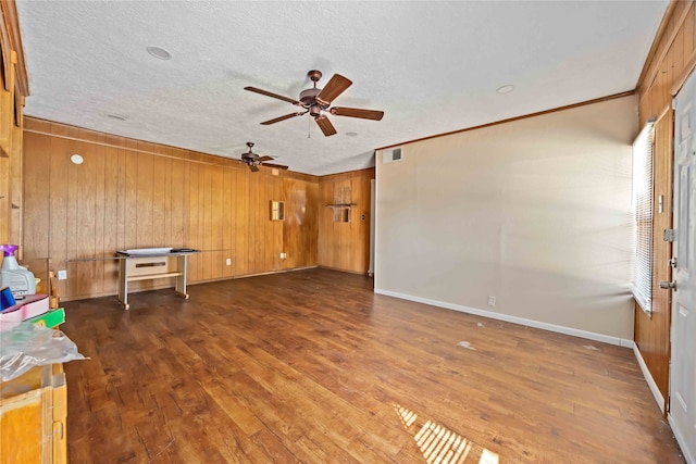 unfurnished living room featuring wooden walls, dark hardwood / wood-style flooring, and a textured ceiling