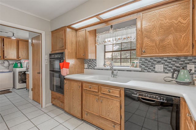 kitchen with backsplash, sink, black appliances, light tile patterned floors, and washing machine and dryer