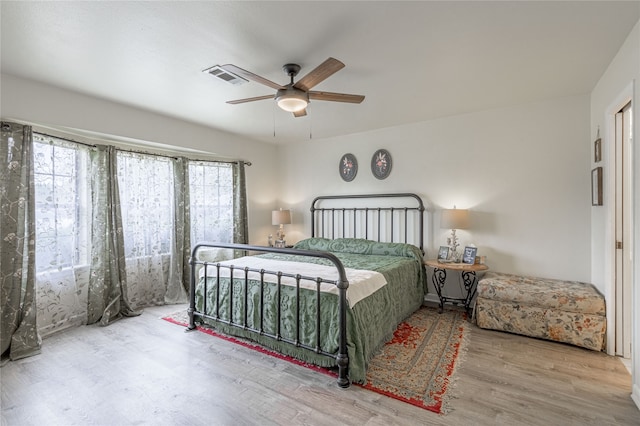 bedroom with hardwood / wood-style flooring, multiple windows, and ceiling fan