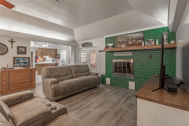 living room with wood-type flooring, a textured ceiling, vaulted ceiling, and ceiling fan