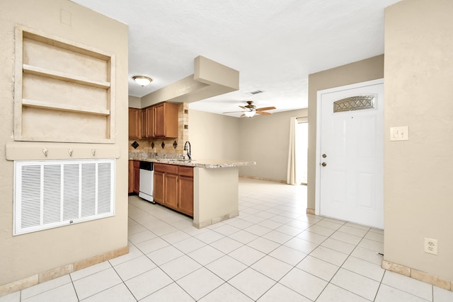 kitchen with white dishwasher, kitchen peninsula, backsplash, and light tile patterned floors