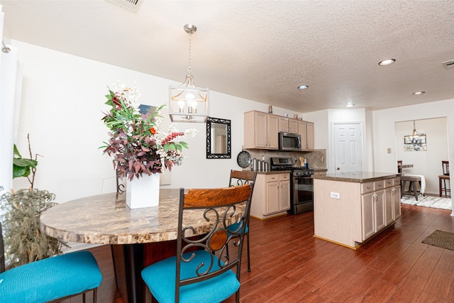 kitchen featuring dark wood-type flooring, a kitchen island, stainless steel appliances, and a notable chandelier