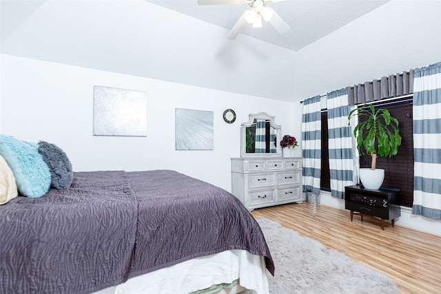 bedroom with ceiling fan, vaulted ceiling, and light wood-type flooring