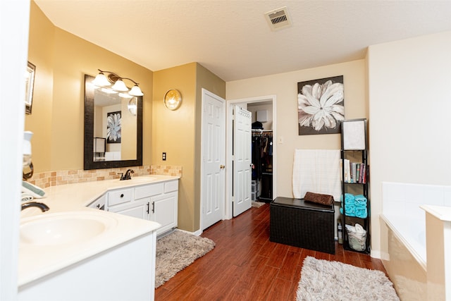 bathroom featuring a bathing tub, hardwood / wood-style floors, vanity, and a textured ceiling