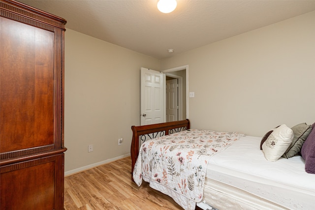 bedroom with a textured ceiling and light hardwood / wood-style floors