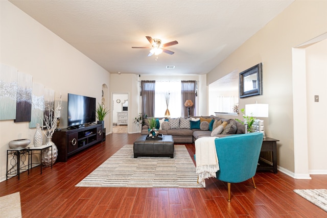 living room featuring ceiling fan, dark hardwood / wood-style flooring, and a textured ceiling