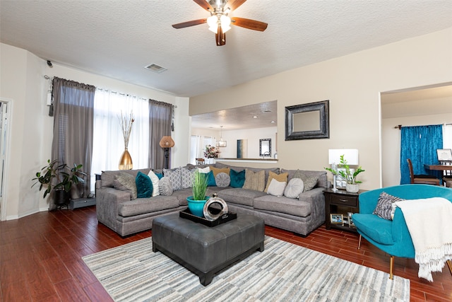 living room featuring hardwood / wood-style floors, ceiling fan with notable chandelier, and a textured ceiling