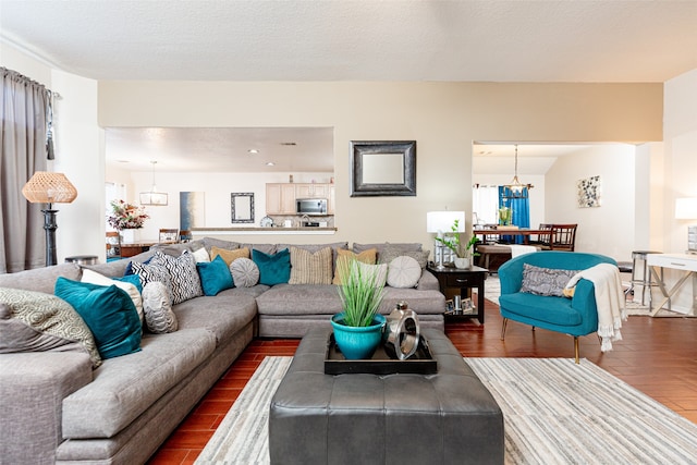 living room with a notable chandelier, dark hardwood / wood-style floors, and a textured ceiling