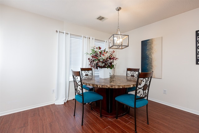 dining space featuring dark wood-type flooring and an inviting chandelier