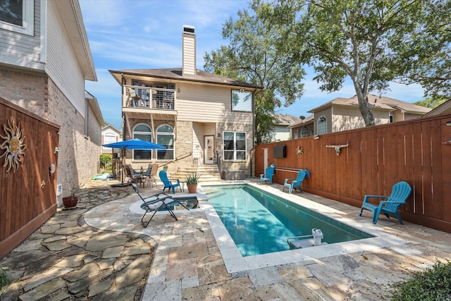 rear view of house with a patio area, a balcony, and a fenced in pool